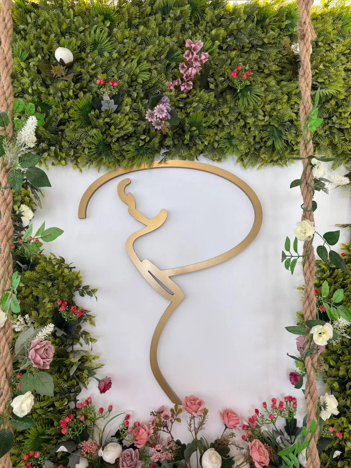 Logotipo dorado de Privilegios sobre muro de flores